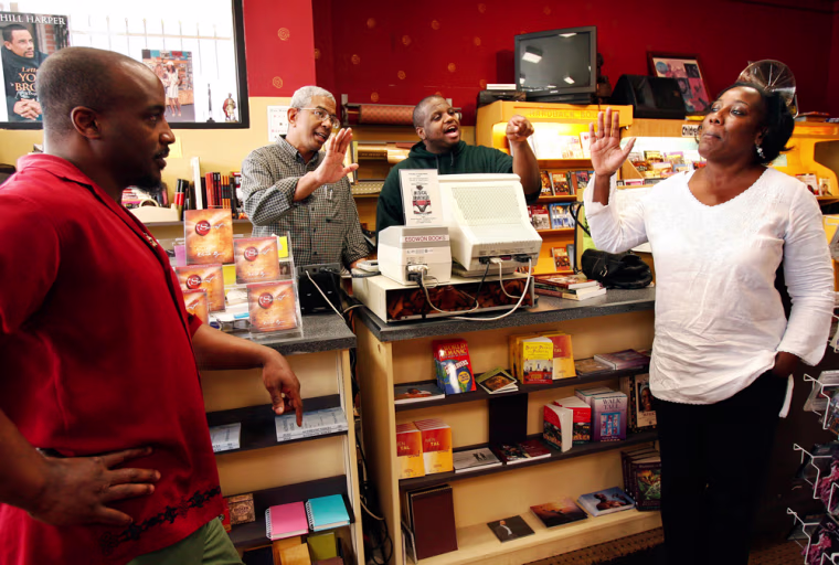 ** ADVANCE WEEKEND APRIL 28-29 ** James Fugate, second left, co-owner of Eso Won bookstore, debates local politics  with Joanna Caine, right, and her brother Joe, left, as employee T.C. Strickland joins in, inside the bookstore in the Leimert Park Village section of Los Angeles, April, 6, 2007.  Book-signings there by former President Bill Clinton and NFL player Jerry Rice drew scores to the village from throughout the city who shopped at nearby boutiques and ate at local eateries.(AP Photo/Kevork Djansezian)