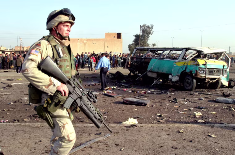 A U.S. SOLDIER GUARDS WRECKAGE OF A MINIBUS AFTER AN EXPLOSION IN BAGHDAD