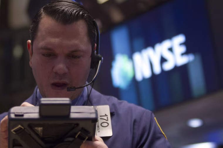 Trader works on the floor of the New York Stock Exchange on Wednesday. The Dow fell almost 200 points as the Federal Reserve said it will cut another $10 billion from its stimulus package.