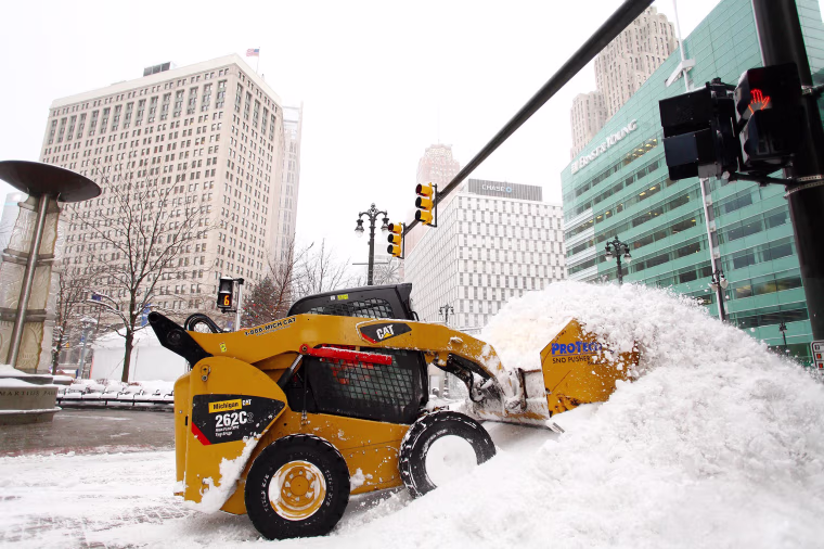 Image: A worker removes snow in Detroit after a January storm.