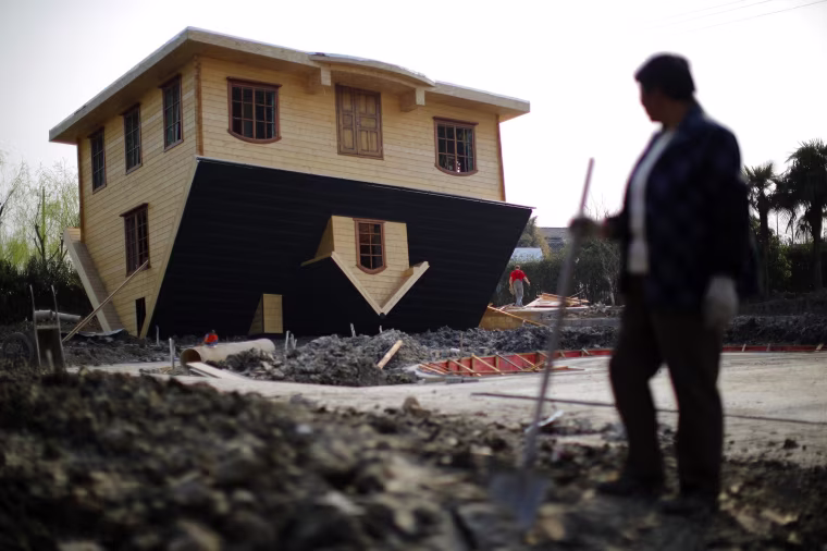 Image: A laborer takes a break as she works at an upside-down house under construction