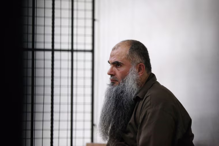 Image: Radical Muslim cleric Abu Qatada looks on from behind bars at the State Security Court in Amman
