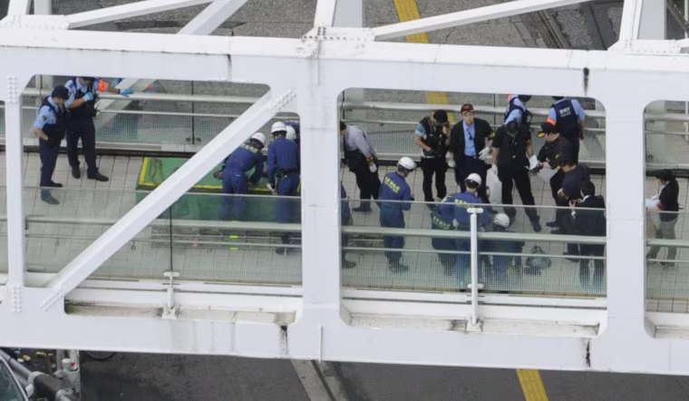 Image: Police officers and fire-fighters investigate the site where a man set himself on fire at a pedestrian walkway near Shinjuku station in Tokyo