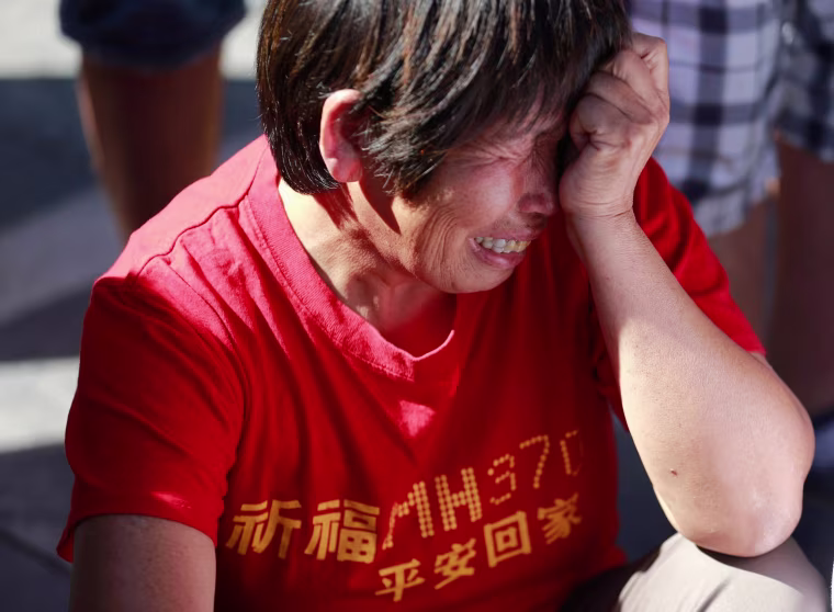 Image: A family member of passengers onboard the missing Malaysia Airlines Flight MH370 cry as they gather to pray Yonghegong Lama Temple in Beijing