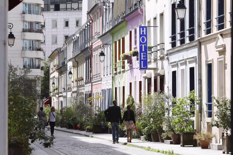 Image: A view shows people walking rue Cremieux, a street lined with colorful, terraced homes, and the hotel "L'Hotel Particulier" located in the 12th district of Paris