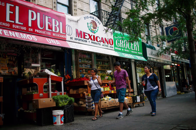 Image: People pass by a Mexican grocery store in Harlem, N.Y., on Aug. 10.