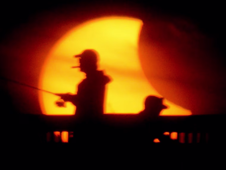 Image: Fishermen try their luck from the M.B. Miller County Pier during a partial solar eclipse