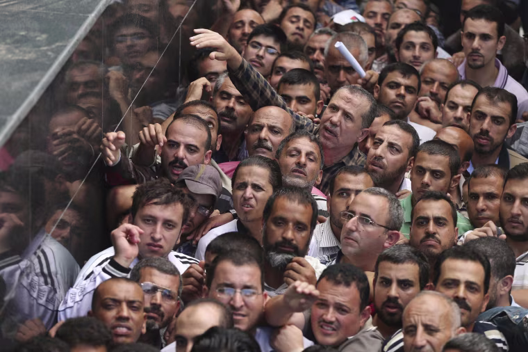 Image: Palestinian Hamas-hired civil servants wait to receive payment outside a post office in Gaza City