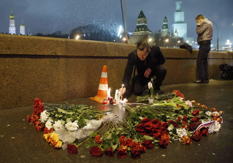 Image: A man places a lit candle at the place where Boris Nemtsov was shot dead near the Kremlin in central Moscow