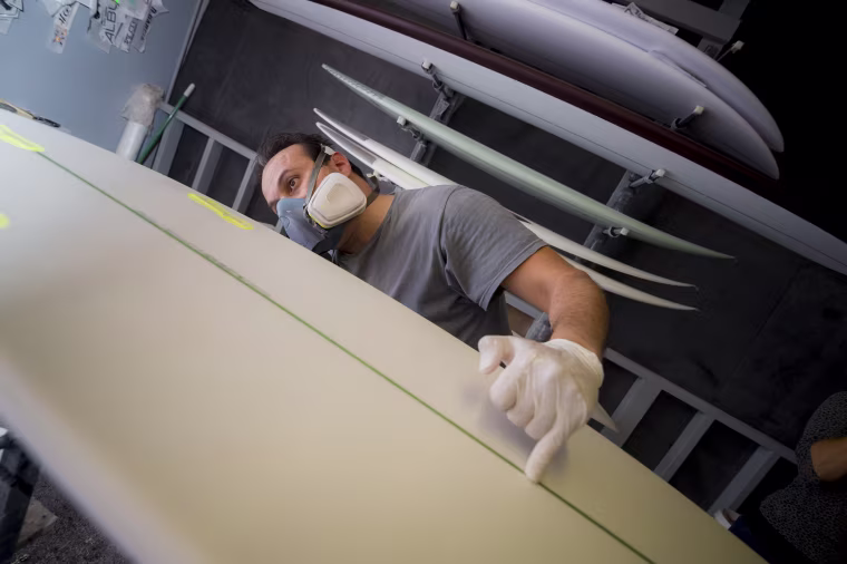 Workers at Arctic Foam prepare the algae board to be coated in fiberglass.