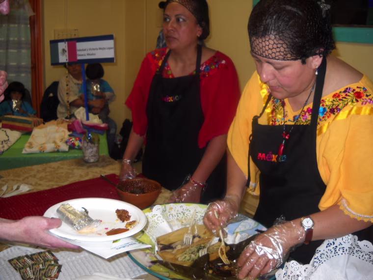 Victoria Lopez (wearing yellow) serves her chepil tamal, a specialty of Oaxaca, Mexico, made with the chepil, an herb with tiny leaves that comes from a shrub, at the TamalFest DC on April 19.