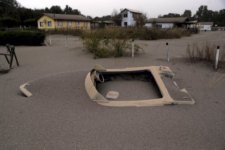 Image: A boat is seen in a house backyard at Ensenada town which is covered with ash from Calbuco volcano