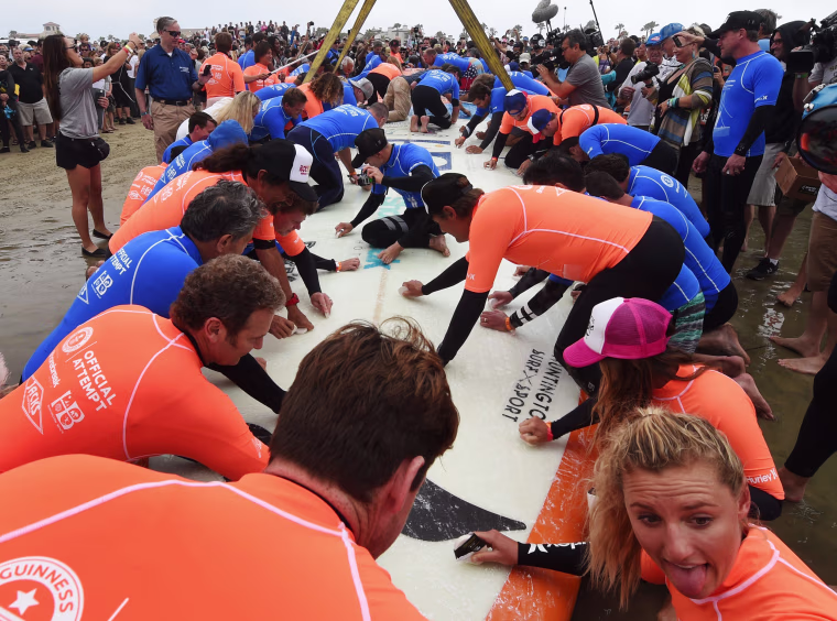 Image: A surfboard is waxed as sixty six surfers from Huntington Beach prepare to break the 'Guinness Book of Records' record