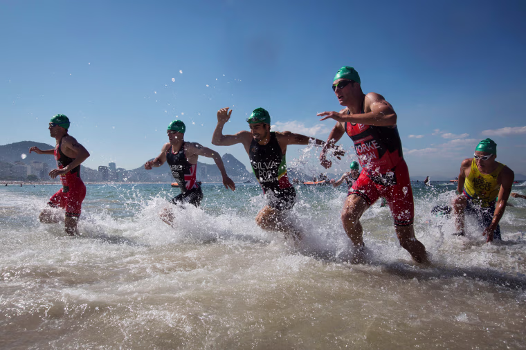 Image: Triathletes exit the water during the men's triathlon