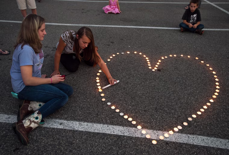 Image: Community supporters light candles in the shape of a heart during a vigil for the killed journalists