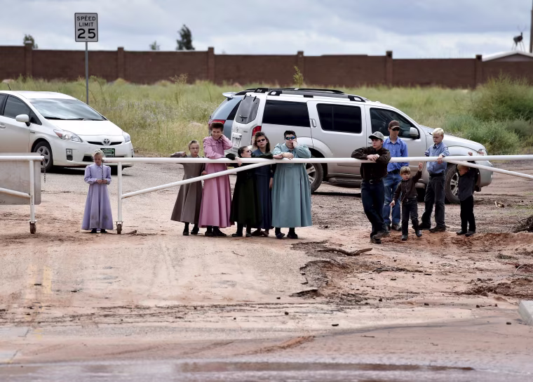 Image: Residents watch rescuers search along the Short Creek after a flash flood in Hildale, Utah