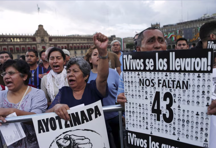 Image: Demonstrators hold placards as relatives (not pictured) of some of the 43 missing students of Ayotzinapa College Raul Isidro Burgos attend a news conference after a private meeting with Mexico's President Enrique Pena Nieto in Mexico City