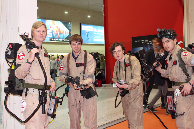 Attendees dressed as characters from "Ghostbusters" pose with proton packs at MCM Comic Con in London.