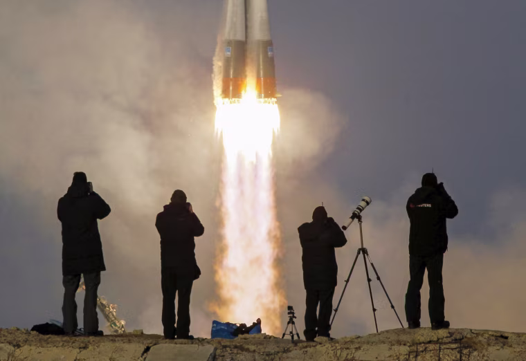 Image: Photographer take pictures as the Soyuz TMA-19M spacecraft carrying the the international Space Station crew as it blasts off from the launchpad at the Baikonur cosmodrome, Kazakhstan