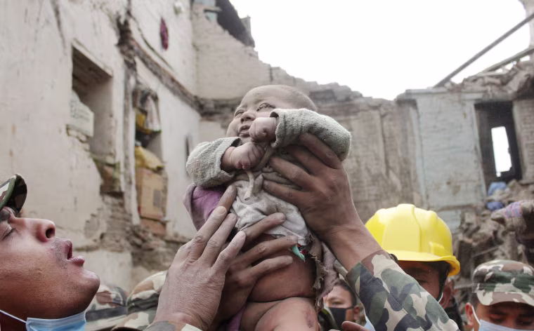 Image: Sonit Awal is held up by Nepalese Army soldiers after being rescued from the rubble of his house