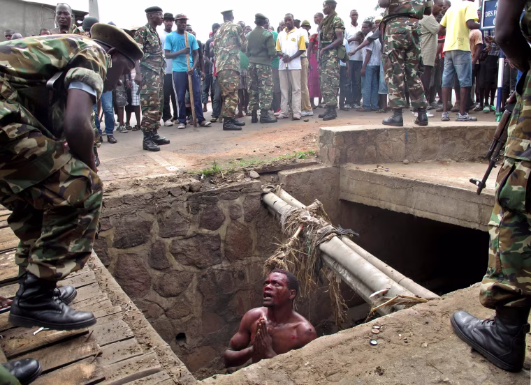 Image: A man begs for help from the military as he stands in a drain