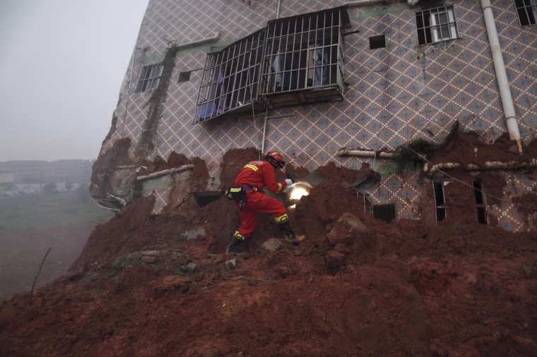Image: A firefighter uses a flashlight to search for survivors at a damaged building at the site of a landslide at an industrial park in Shenzhen