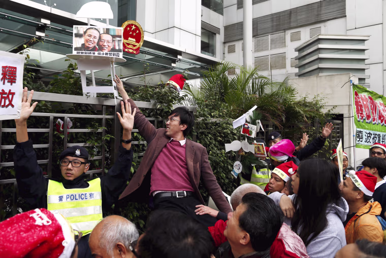 Image: A pro-democracy demonstrator holds up prop with a photo of Liu and his wife Liu Xia
