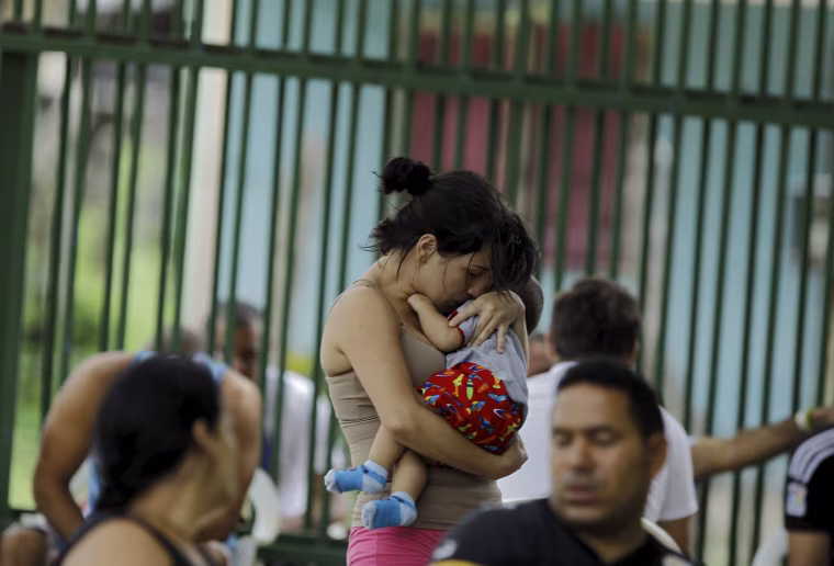 Image: Cuban migrant Sylenay Valle holds her 10 month-old son Yeryko at a shelter in Liberia