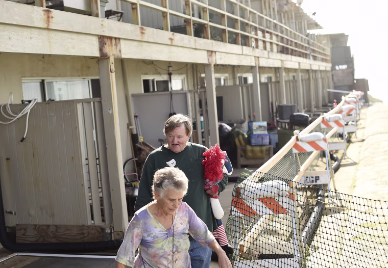 Image: Garth Yeaman and his friend Janet Breger walk along a crumbling cliff outside his apartment building, which is in danger of collapsing due to El Nino storm erosion, in Pacifica, California