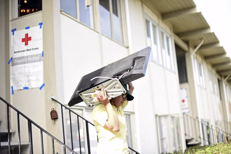 Image: Brandy McDaniel carries a television from her apartment building, which is in danger of collapsing due to El Nino storm erosion, in Pacifica, California