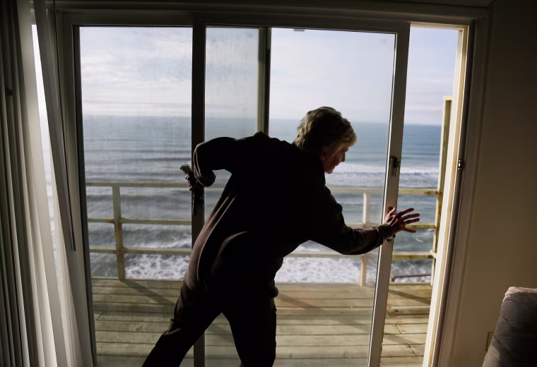 Image: Eileen Horan shuts the door to her patio overlooking the Pacific Ocean