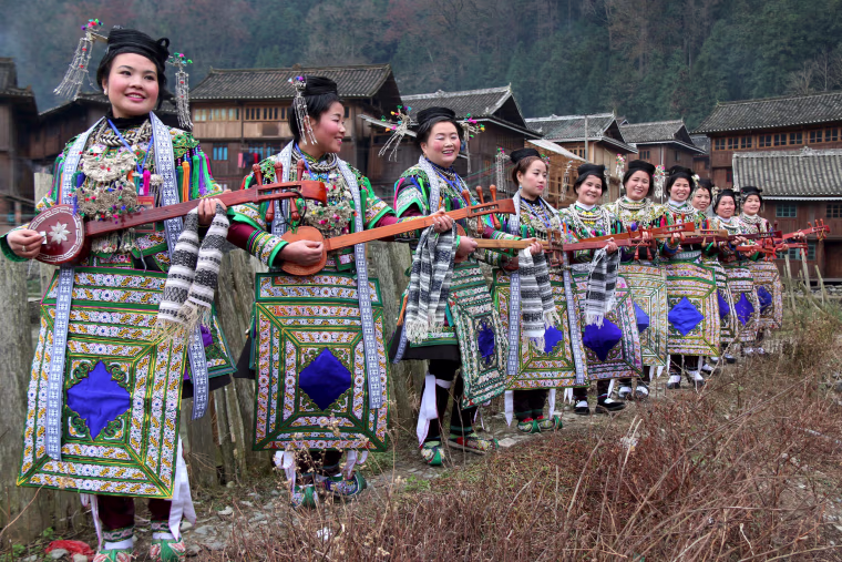 Image: Ethnic Dong women wearing traditional costumes, hold \"pipas\", a traditional instrument