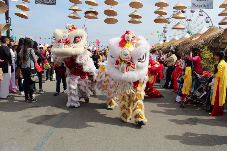 Vietnamese lion dancers make their way under the cultural village's back gate.