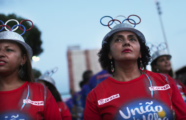 Image: Women with the Uniao da Ilha do Governador samba school wear Olympic ring hats during a pre-Carnival rehearsal