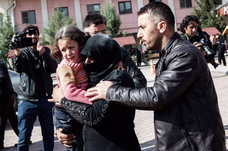 Image: A Turkish man helps a Syrian woman carrying a wounded Syrian girl to a hospital in Kilis, Turkey after airstrikes in Northern Syria