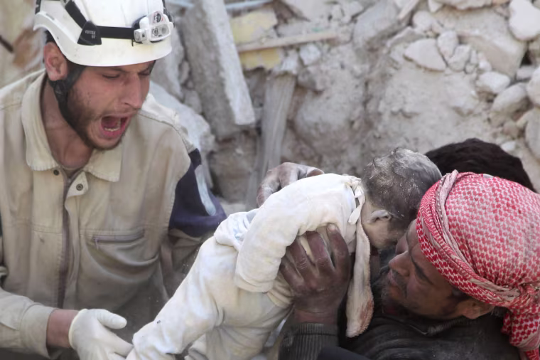 Image: A man holds the body of a dead child as a civil defence member reacts after airstrikes by pro-Syrian government forces in the rebel held al-Qaterji neighbourhood of Aleppo,