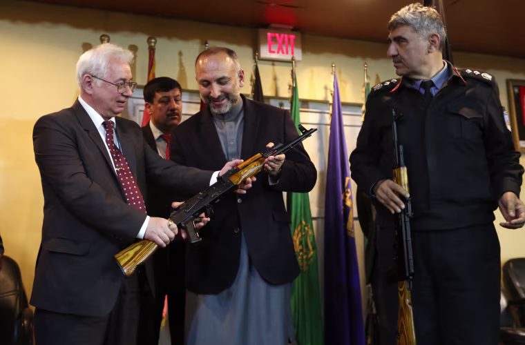 Image: Russia's Ambassador to Kabul Alexander Mantytskiy hands an AK-47 to Afghan National Security Adviser Mohammad Hanif Atmar