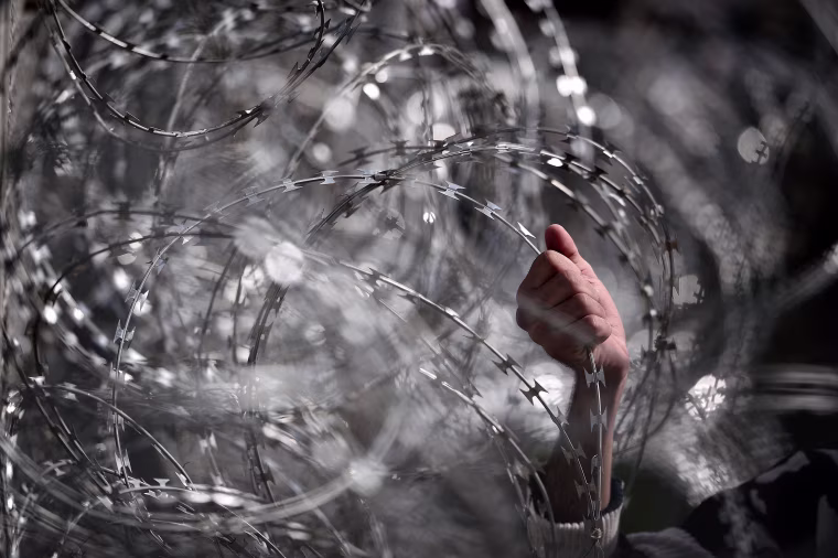 Image: Migrant holding wire