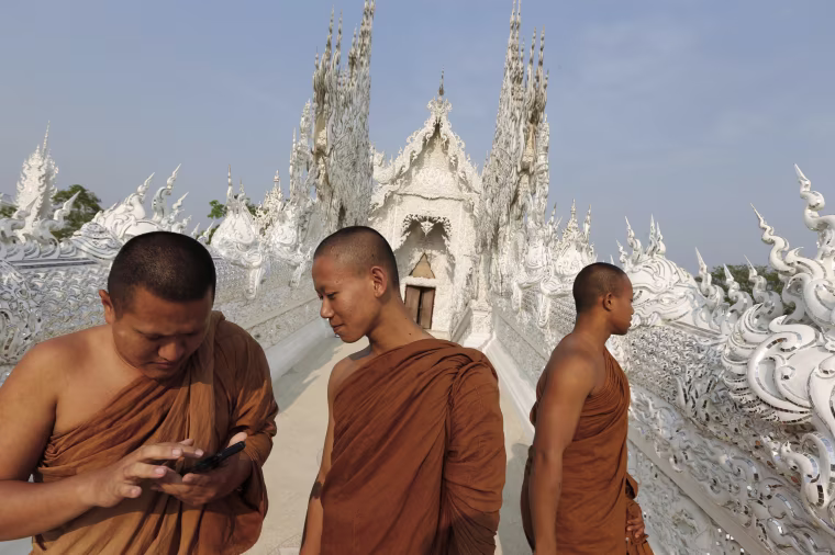 Buddhist monks tour Wat Rong Khun, also know as the White Temple, designed by Thai artist Chalermchai Kositpipat in Chiang Rai Province, Thailand.