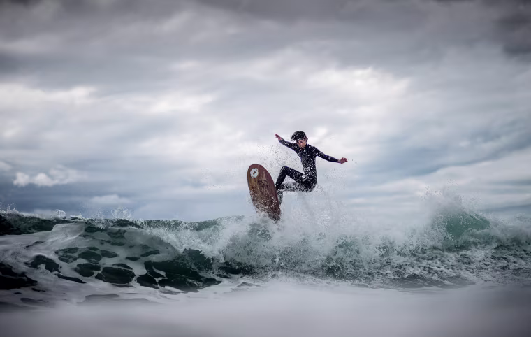 Image: A surfer rides a wave on a day of swells generated by strong winds