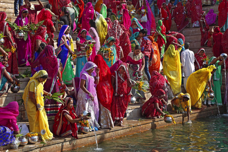Image: Hindu women collect water from the Pushkar lake to pour on idols of Lord Shiva