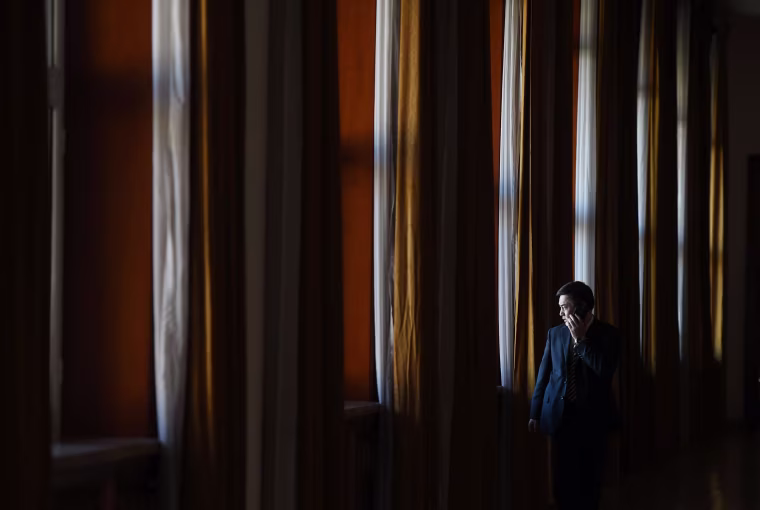 Image: An official makes a phone call outside a group meeting for Tibetan delegates
