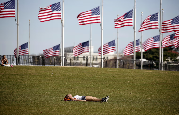 Image: A woman sunbathes on a unseasonably warm day in Washington