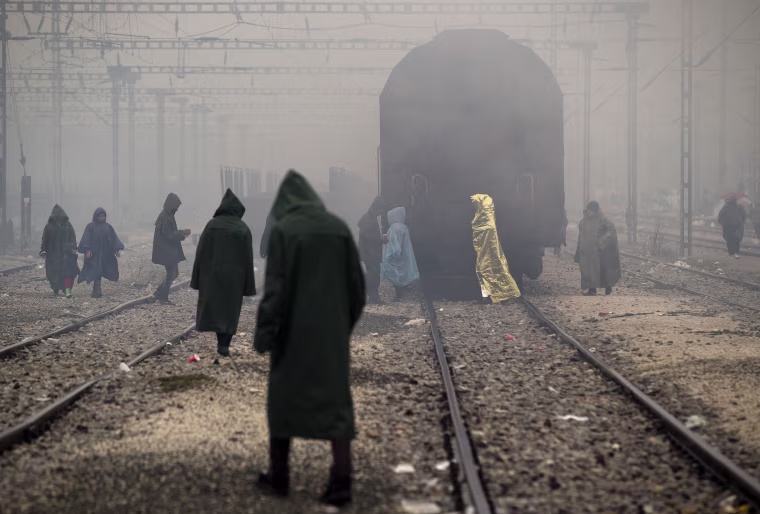 Image: Migrants walk on railway tracks at the northern Greek border station of Idomeni