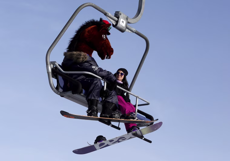 Image: A snowboarder wearing a mask of a horse head rides a lift uphill at the Bobrovy Log ski resort in the suburbs of Krasnoyarsk