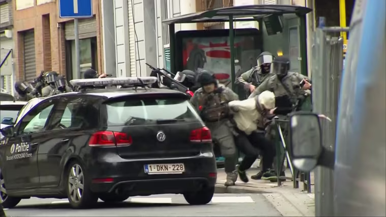 Armed security officers dragged a man from a Molenbeek apartment at gunpoint after shots were fired in a terror raid related to the November Paris attacks.