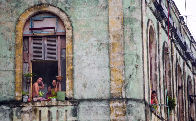Image: Cubans watch from their homes as the motorcade of U.S. President Barack Obama arrives in a section of Old Havana