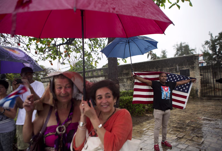 Image: A handful of Cubans gather along the Malecon sea wall under a steady rain