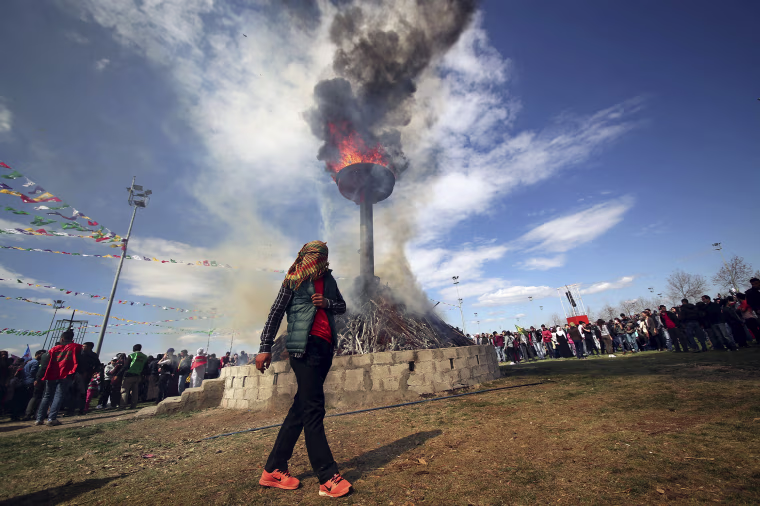 Image: A masked demonstrator walks around a bonfire during a gathering to celebrate the spring festival of Newroz in the Kurdish-dominated southeastern city of Diyarbakir