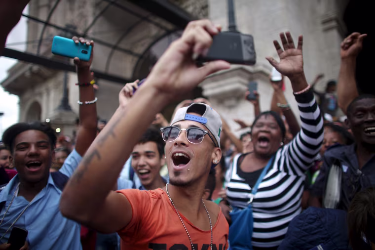 Image: People react as they wait for an eventual visit of U.S. President Barack Obama to downtown Havana